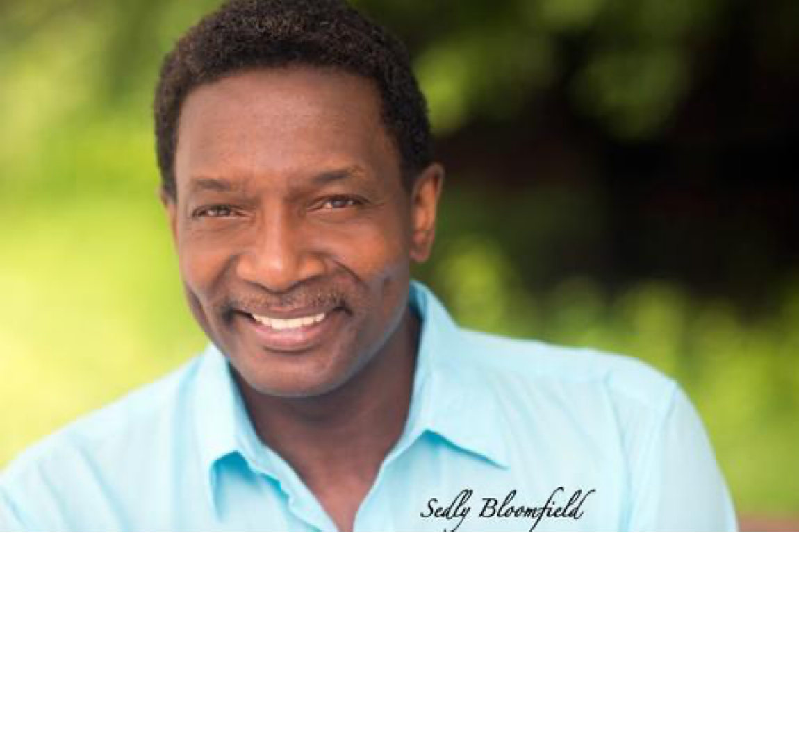 Sedly Bloomfield smiling in a light blue shirt