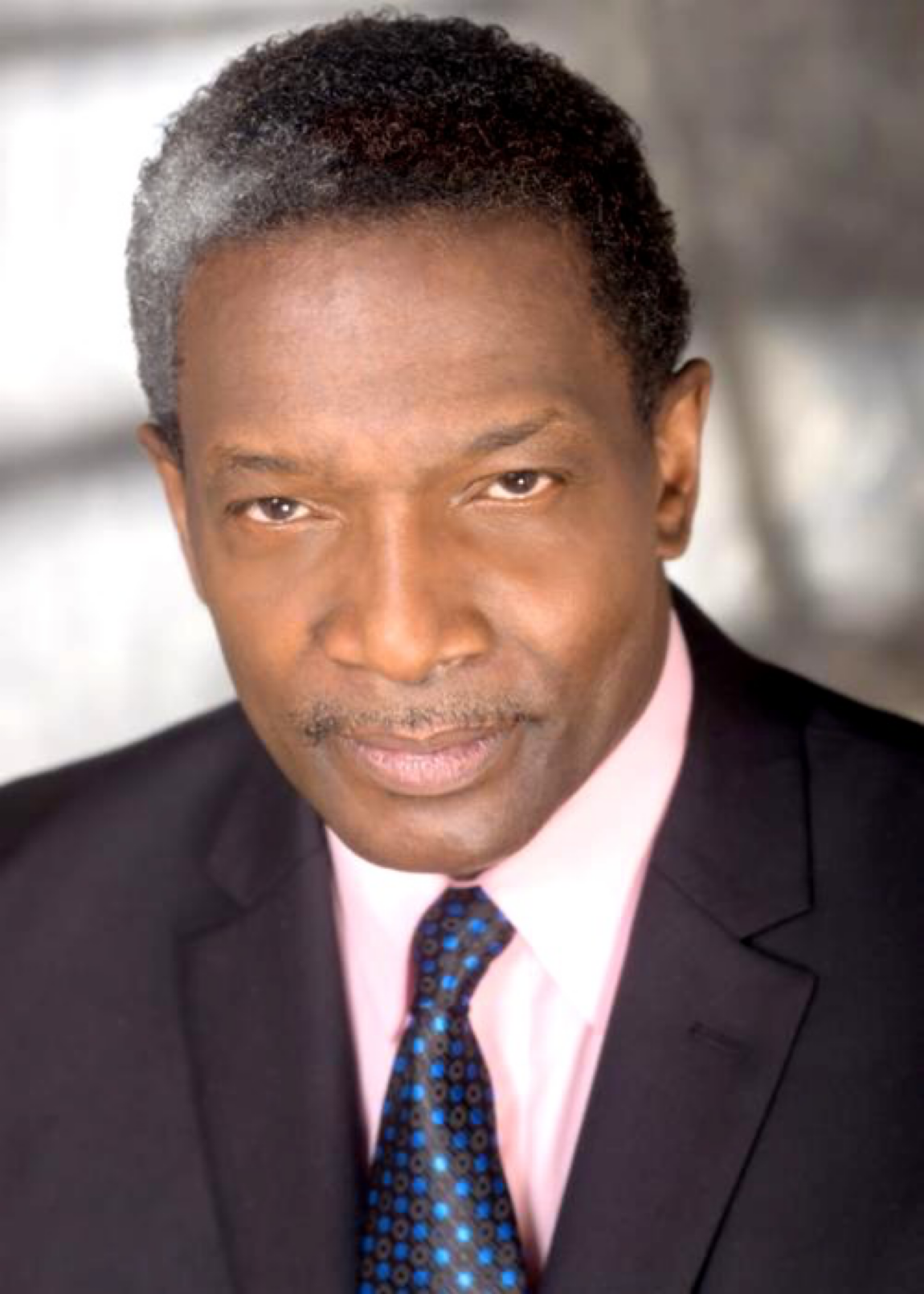 Portrait of Sedly Bloomfield in a dark suit and pink shirt